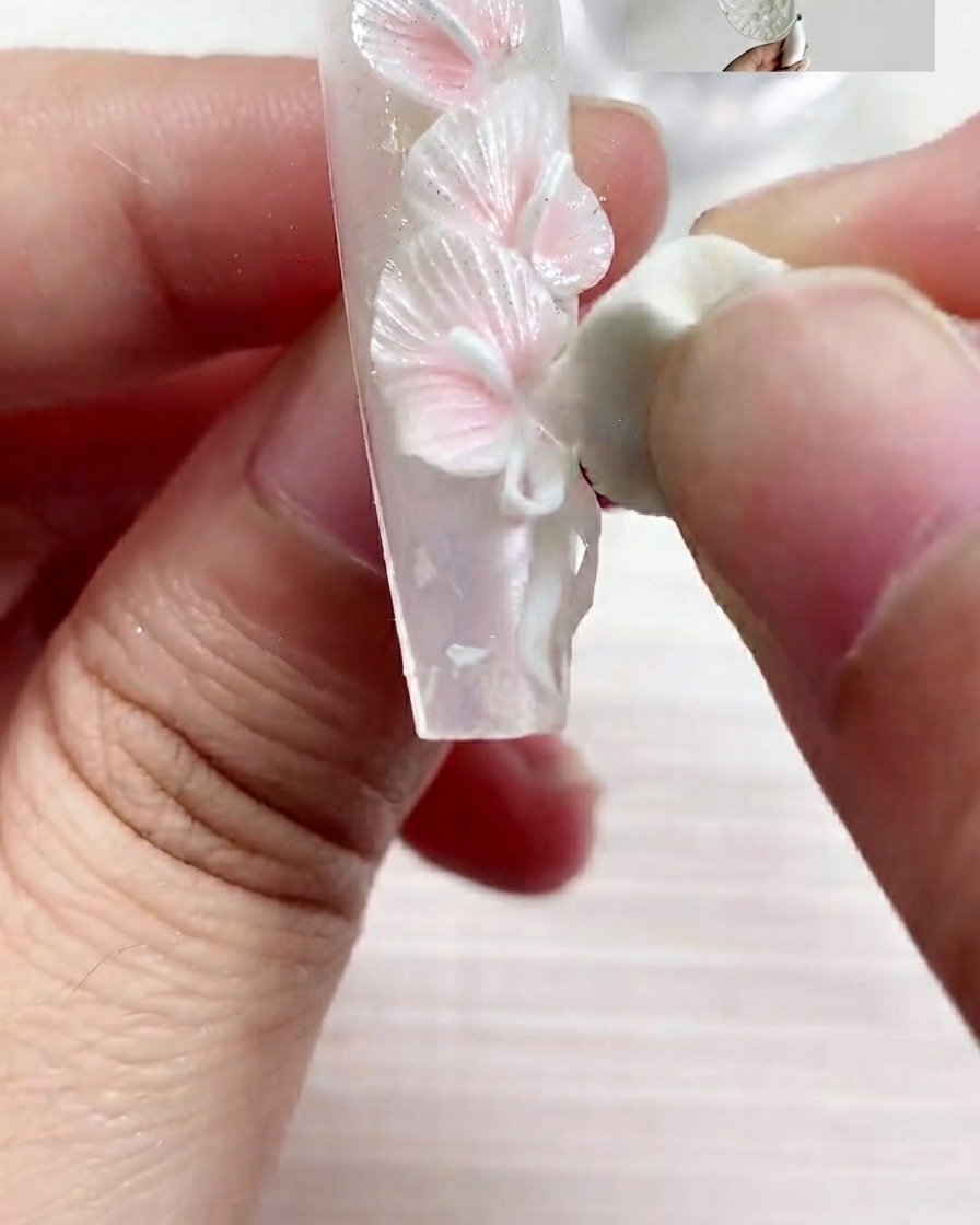 Un pincel plano aplicando gel de textura perlada S03 sobre la superficie de la uña con trazos suaves.
