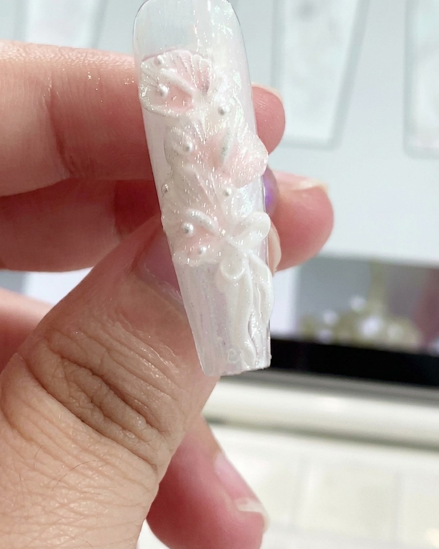 Una herramienta de silicona dando forma a un lazo de cinta de gel en la uña de un dedo decorada.
