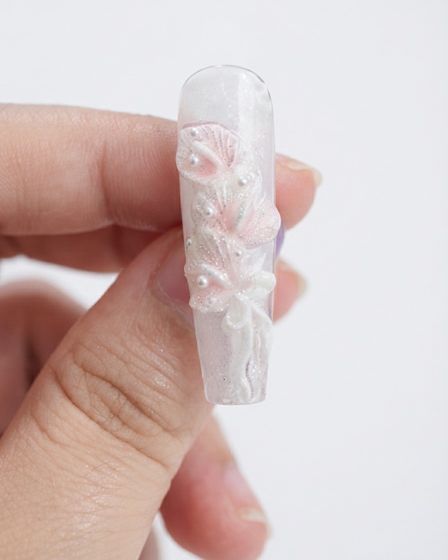Una esponja de maquillaje aplicando gel rosa claro sobre los pétalos de lirio calla blancos esculpidos.