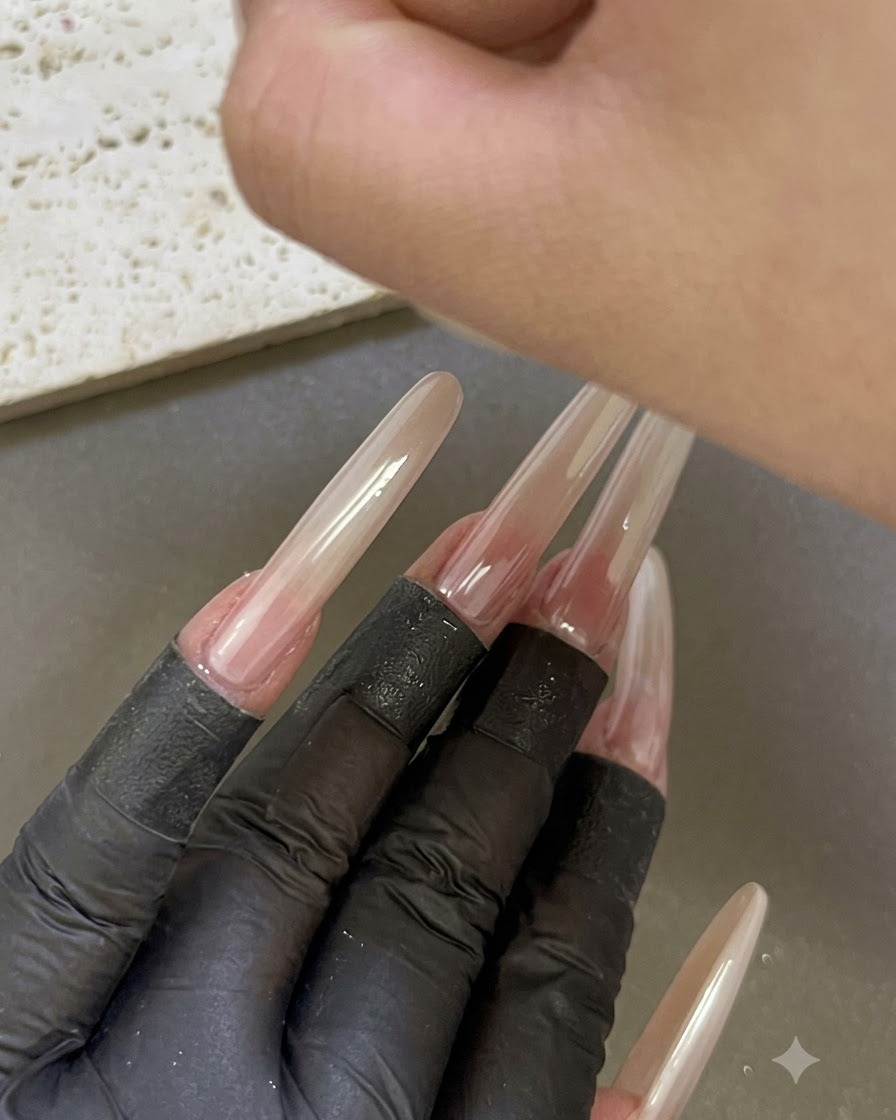 Una mano colocada bajo una lámpara de uñas UV/LED con otros dedos manicurados y extendidos visibles en primer plano.