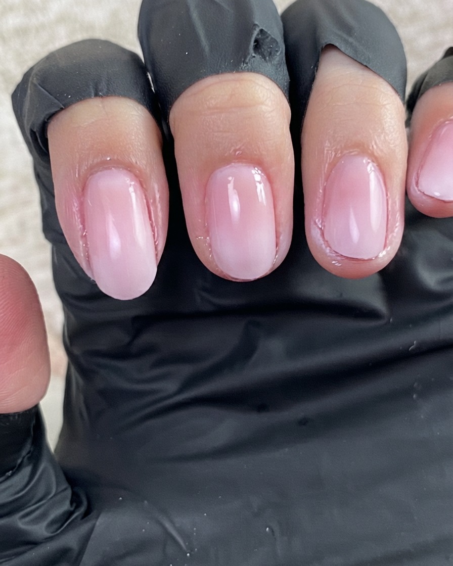 Una vista de cerca de una capa fresca de gel base transparente brillando sobre la superficie de uñas preparadas.