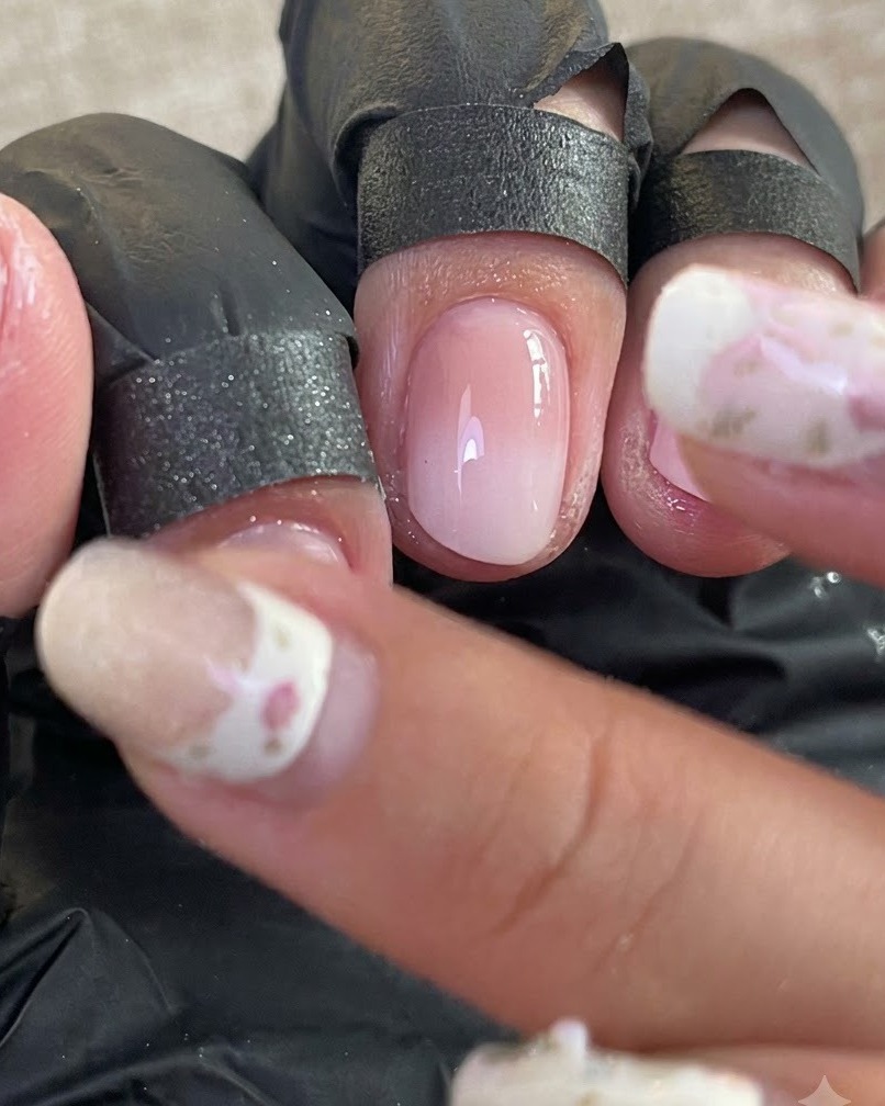 Una vista cercana de uñas preparadas con dedos protegidos por fundas negras durante el proceso de pulido de cromo.
