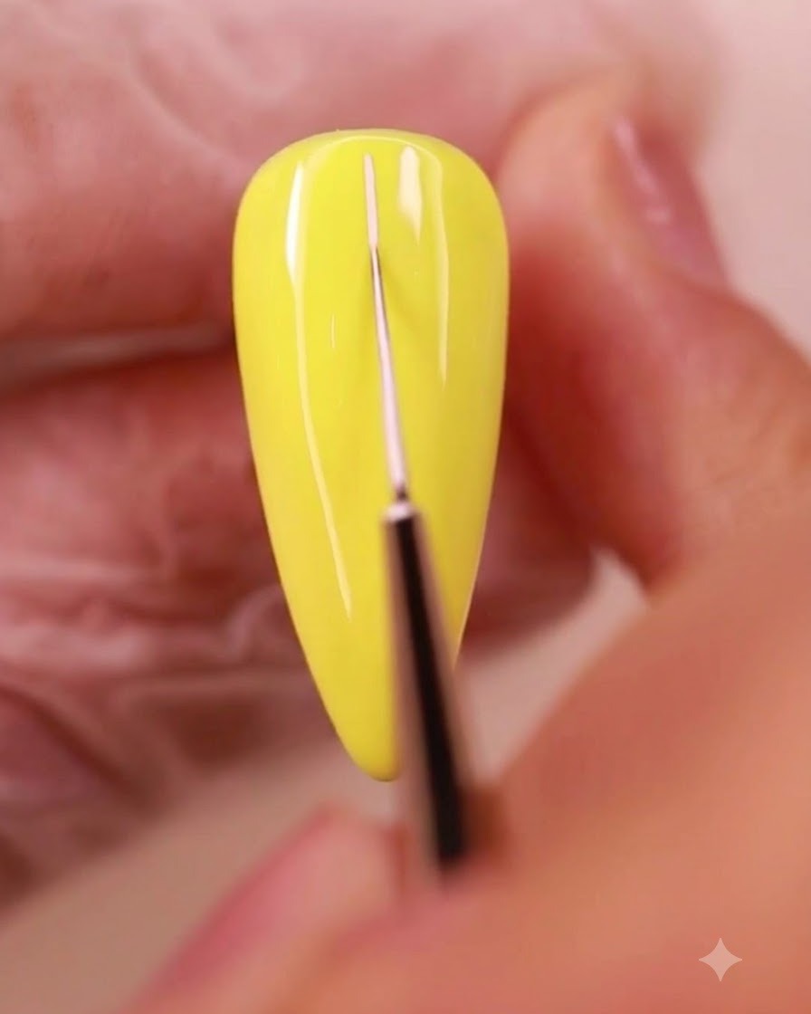 Un pincel delineador fino dibujando finas líneas de cuadrícula blancas sobre la superficie de una uña pintada de amarillo.