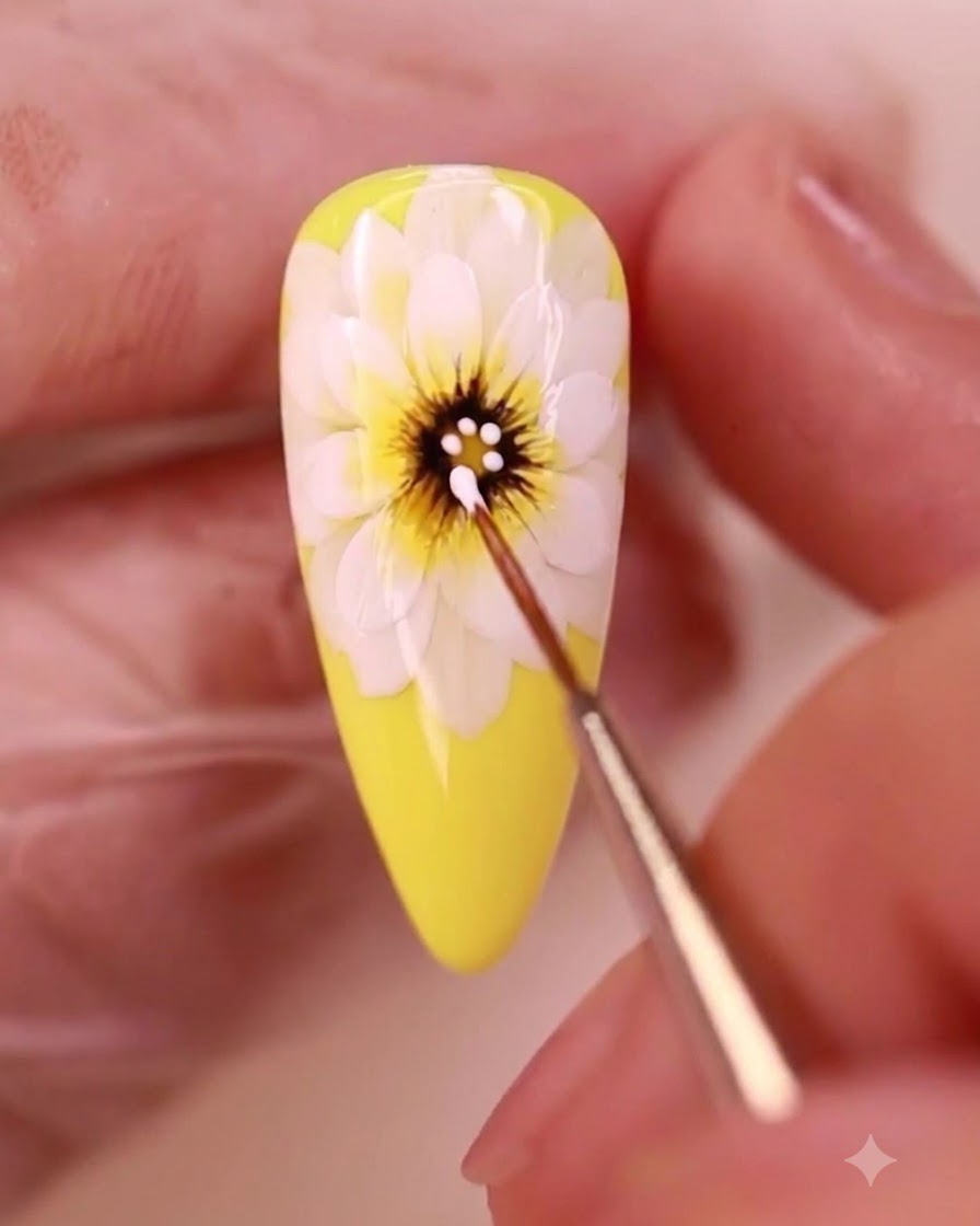 Un pincel de detalles aplicando puntos de gel blanco sobre el centro oscuro de una margarita amarilla pintada.