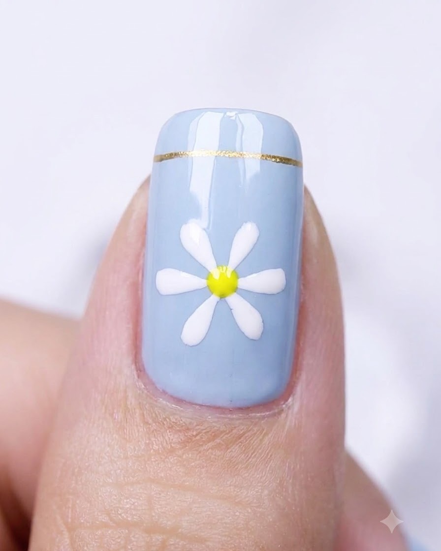 Primer plano de una uña azul con un diseño de margarita colocada dentro de una lámpara de curado.