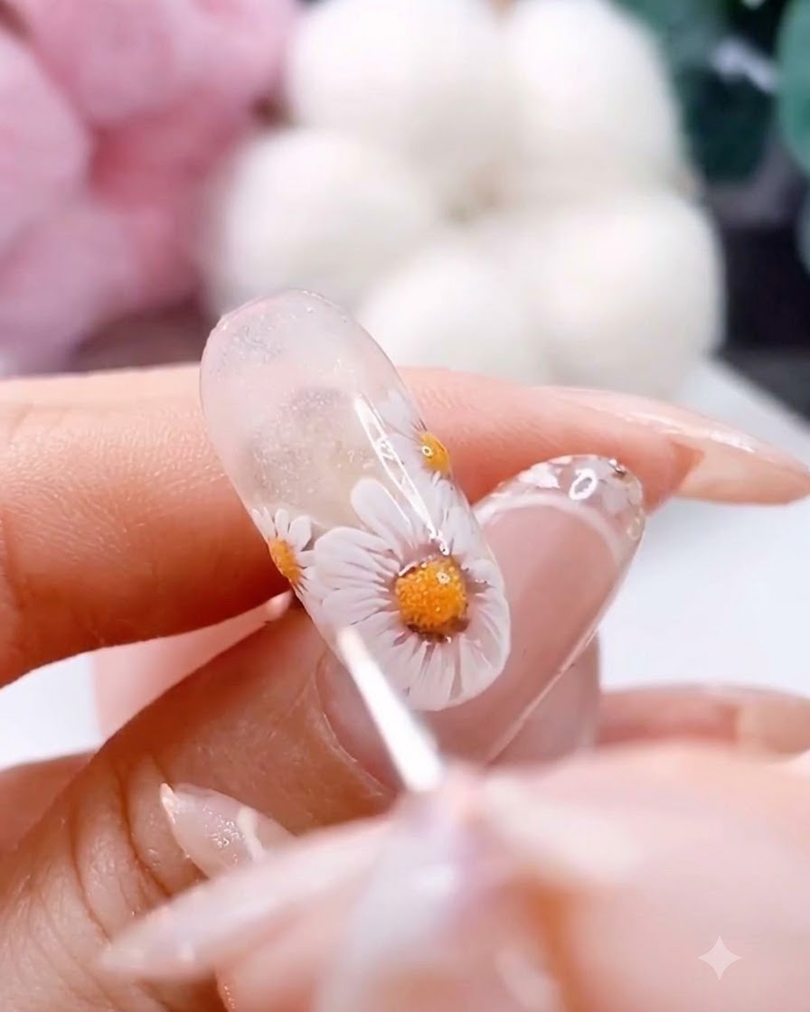 Un pincel de detalle fino añadiendo pequeños puntos blancos y marrones alrededor del centro de una margarita pintada.