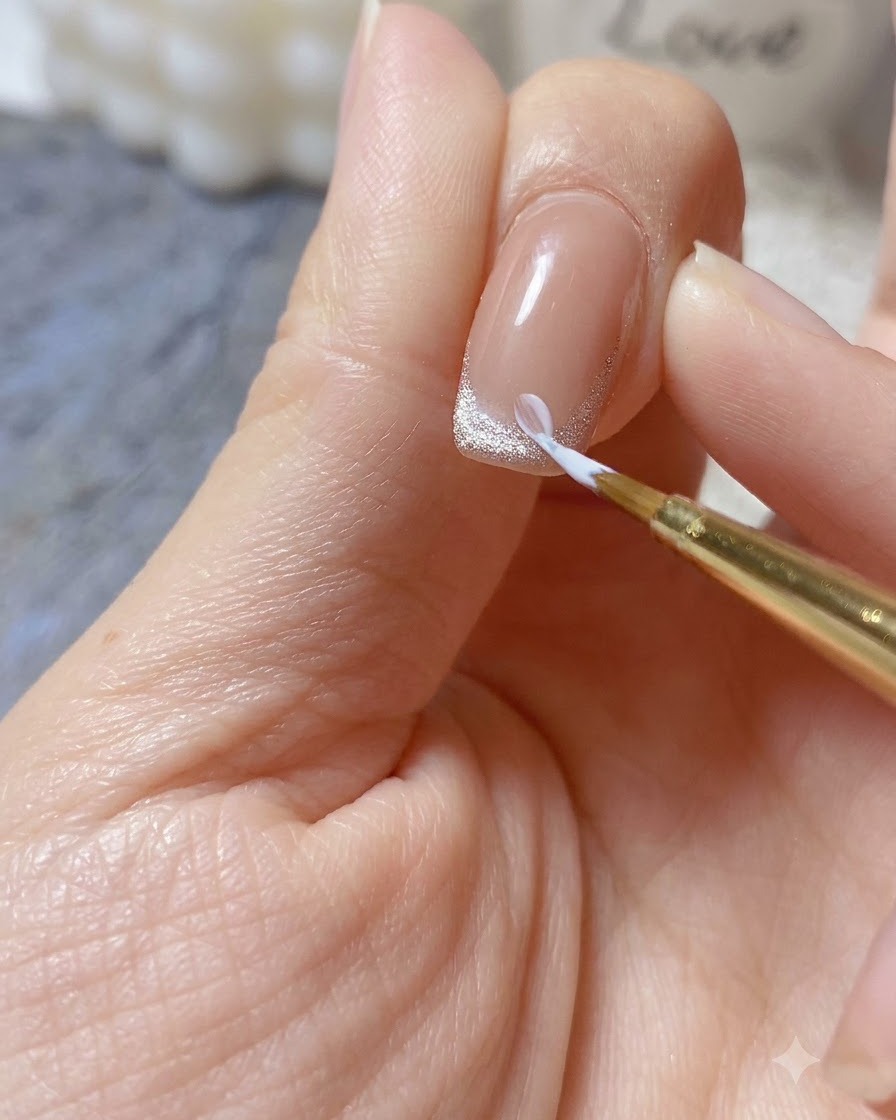 Un pincel fino aplicando una gota de gel de relieve blanco espeso para formar un pétalo de margarita 3D en la punta de la uña.