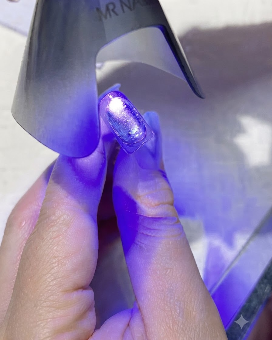 Una mini lámpara de uñas UV/LED morada portátil que emite luz morada directamente sobre una uña recubierta.