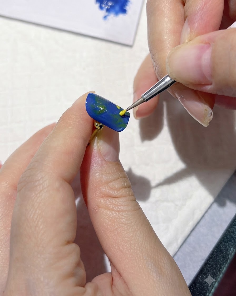 Una herramienta de detalle fina aplicando puntos amarillos para marcar los centros de las flores en una uña azul.