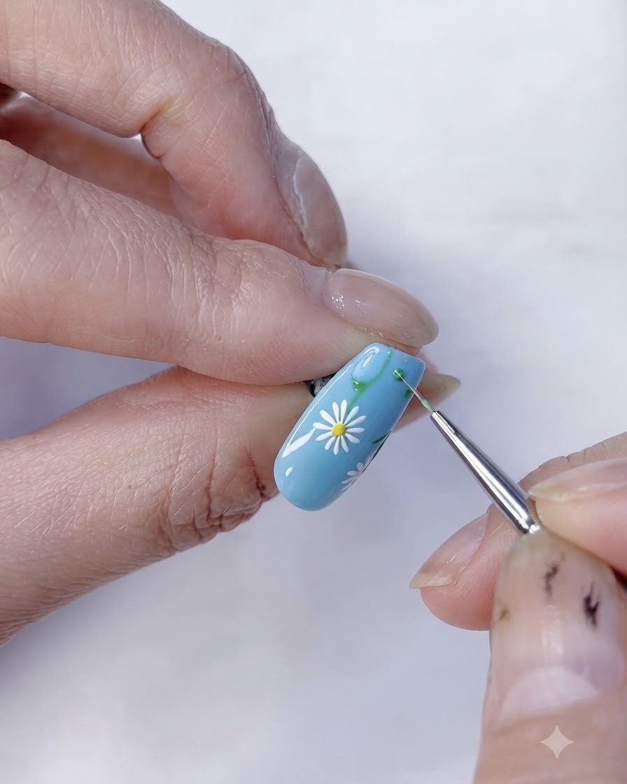 Vista en primer plano de un diseño completado de nail art floral de margaritas sobre una base azul claro.