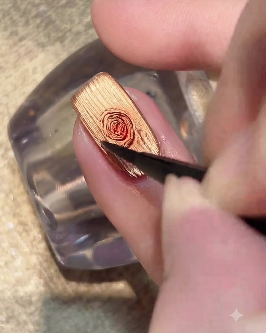 Un pincel aplicando una capa transparente de gel blooming sobre la superficie de la uña con ojo de gato dorado.