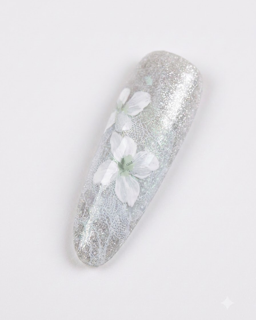 Primer plano de una uña manicurada con delicadas flores blancas con un suave sombreado gris sobre un fondo gris azulado brillante.