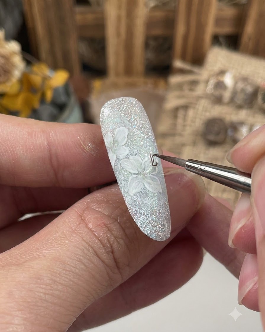 Un pincel fino aplicando una capa de gel sellador sobre el diseño detallado de la flor en una uña decorada.