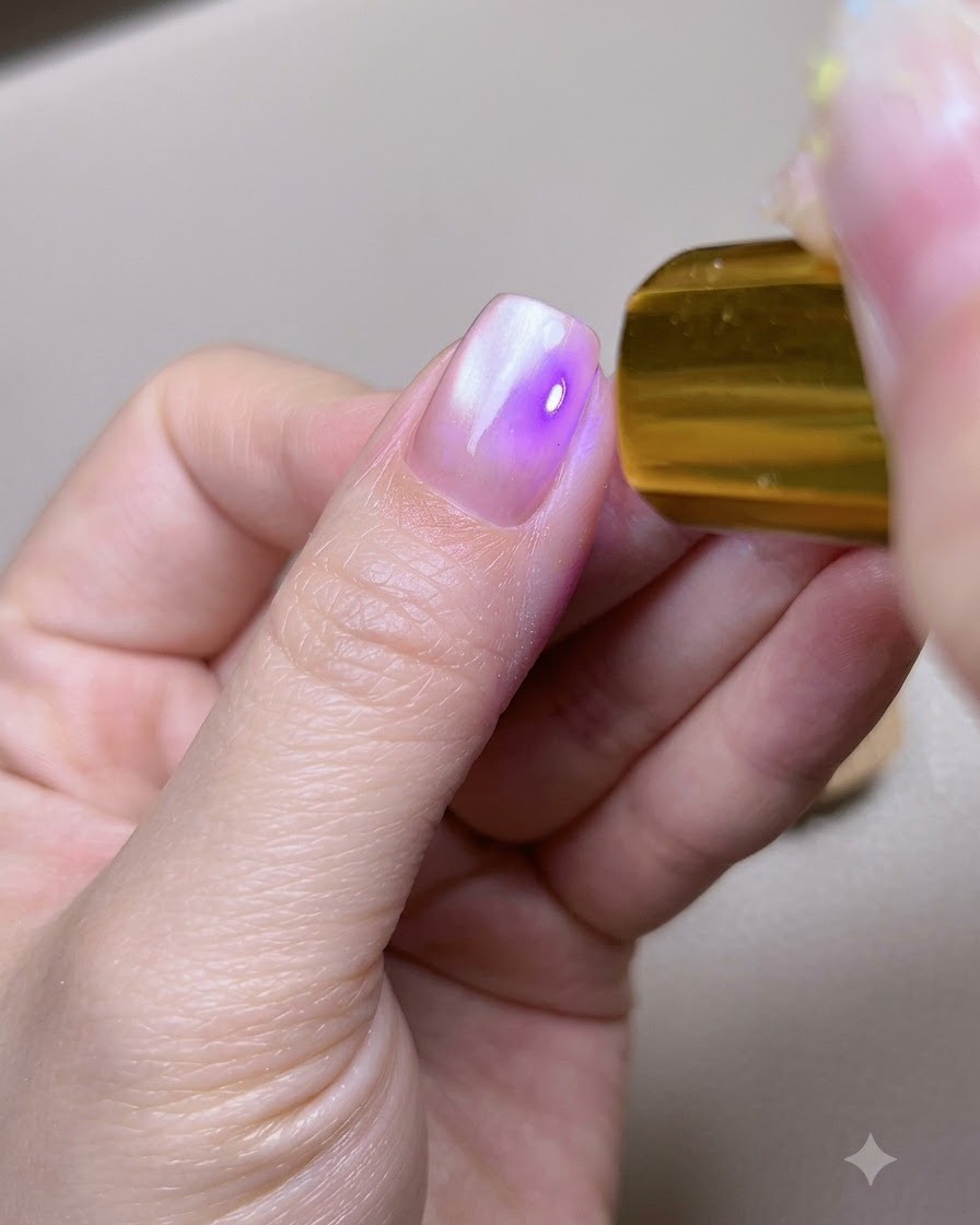 Una uña de pulgar colocada debajo de una lámpara portátil de curado UV LED dorada.