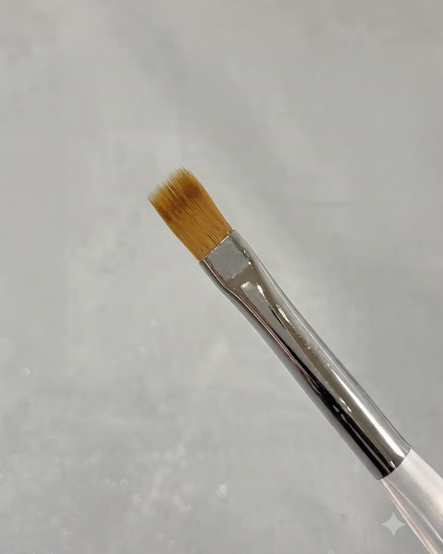 Un primer plano de un pincel fino de barrido para nail art con cerdas suaves de color marrón.