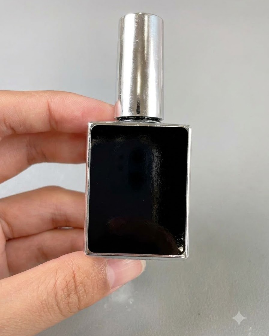 Un pequeño frasco rectangular negro de esmalte en gel para uñas sostenido por una mano sobre un fondo neutro.