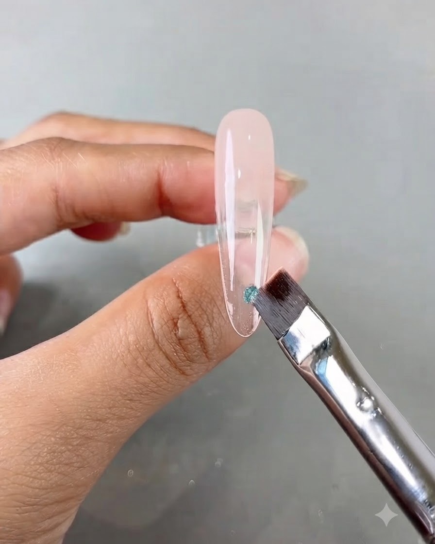 Un pincel de uñas aplicando una pequeña pieza de lentejuela azul sobre una uña postiza transparente larga.