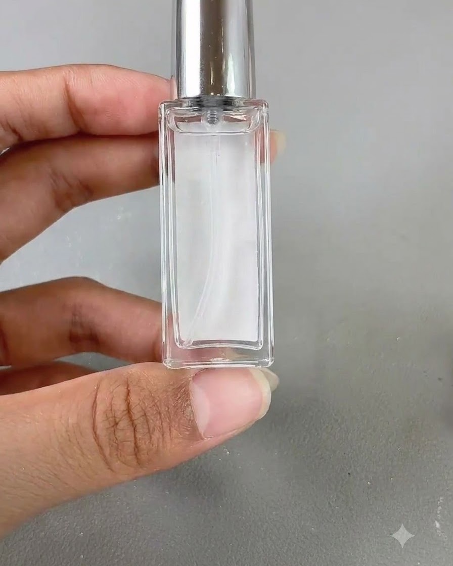 Un pequeño frasco de vidrio de líquido floreciente sostenido contra un fondo neutro.