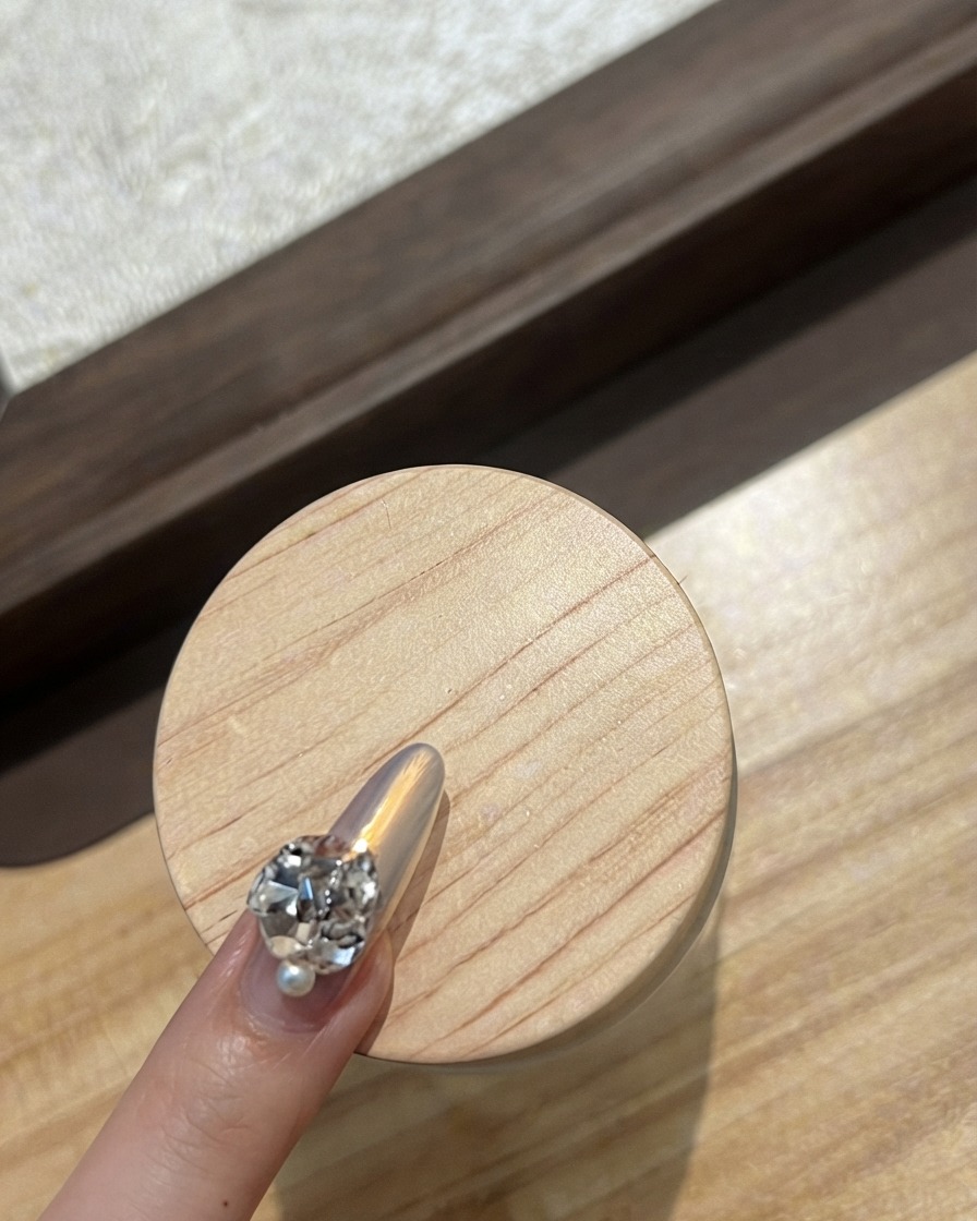 Primer plano de la uña de un dedo índice decorada con una fila curva de diminutos y brillantes estrases.