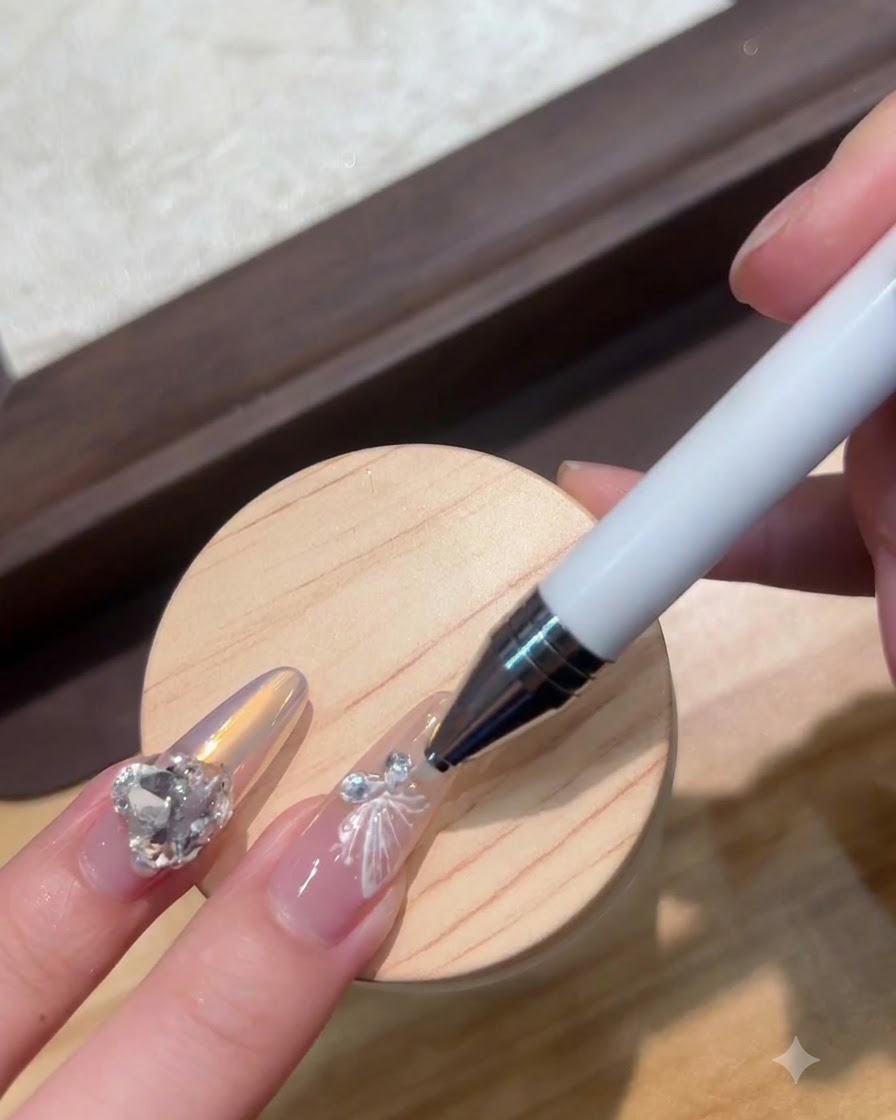 Un puntero colocando un pequeño cristal junto a un dije de mariposa blanca para uñas.