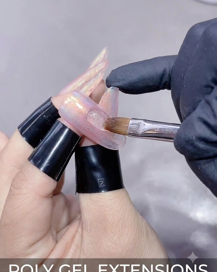 Un primer plano de una mano sosteniendo una varita magnética sobre una uña alargada para moldear el reflejo del gel ojo de gato.