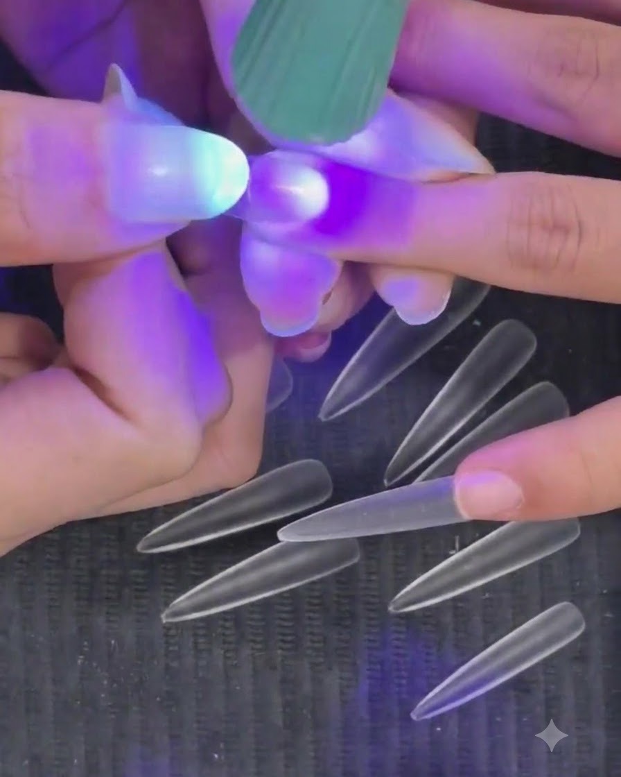 Una mano sosteniendo una mini linterna UV LED de color púrpura sobre una uña para curar un tip semi-curado.