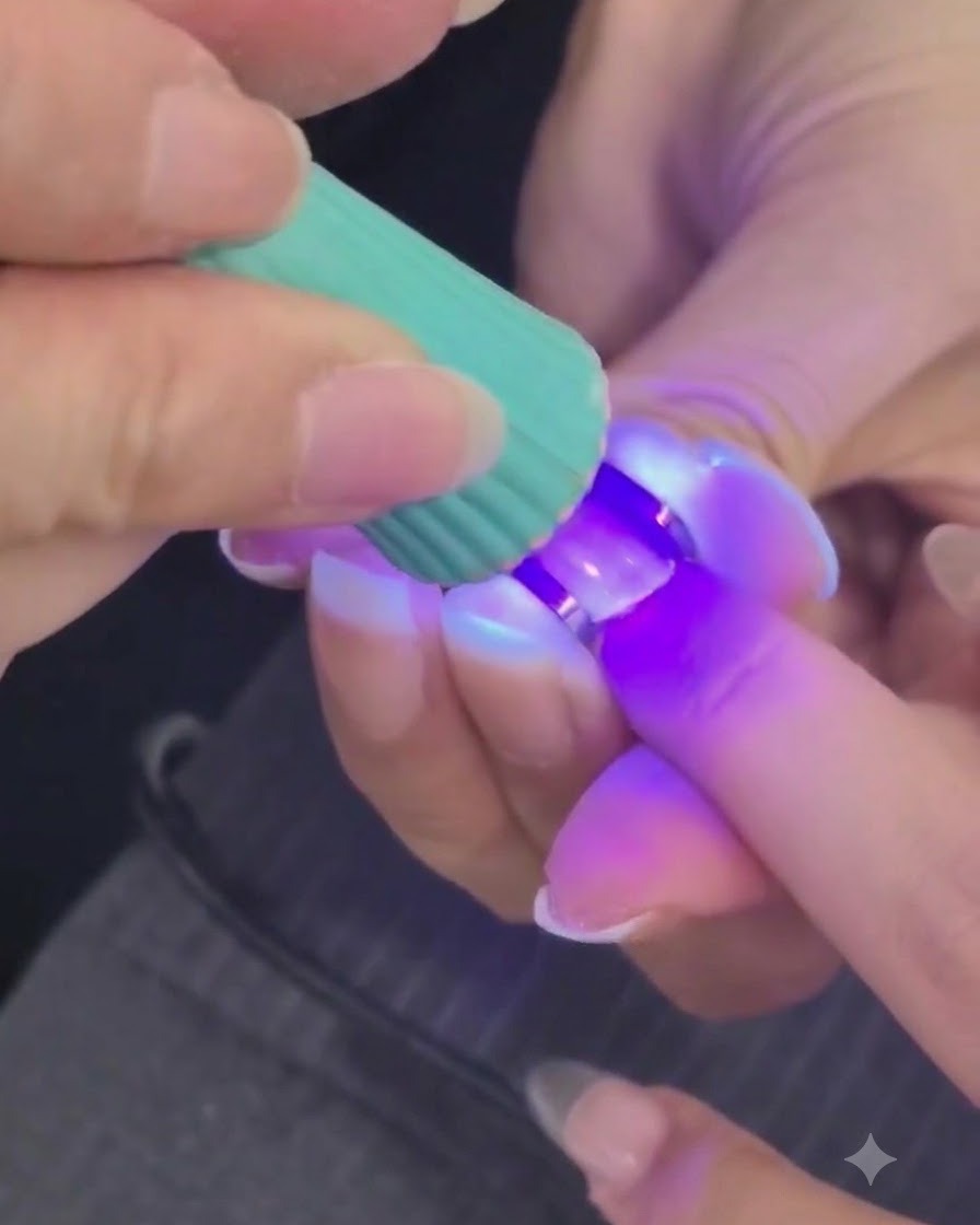 Una mini lámpara UV o LED curando una capa de gel estructural en una uña.