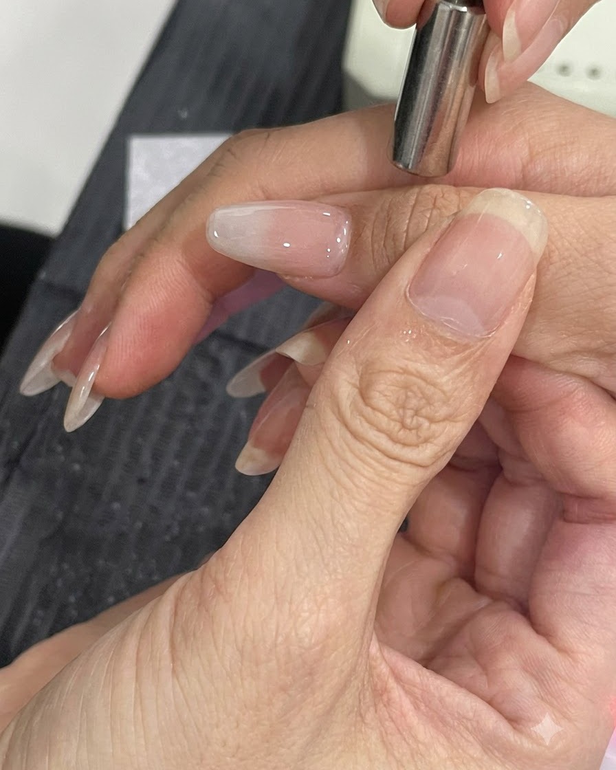Una pequeña herramienta magnética sostenida cerca del lateral de una uña arreglada para desplazar las partículas de brillo cat-eye.