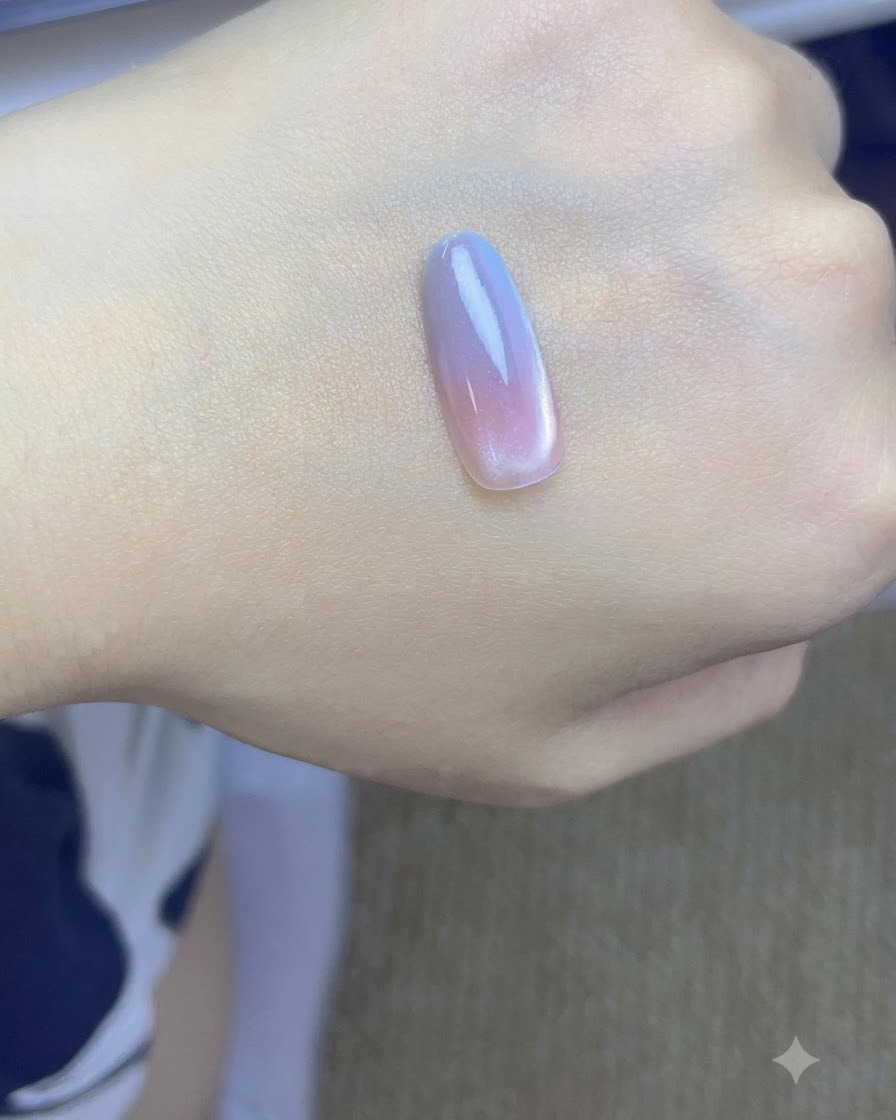 Una punta de uña con capas de degradado rosa y azul curándose bajo una lámpara UV/LED.