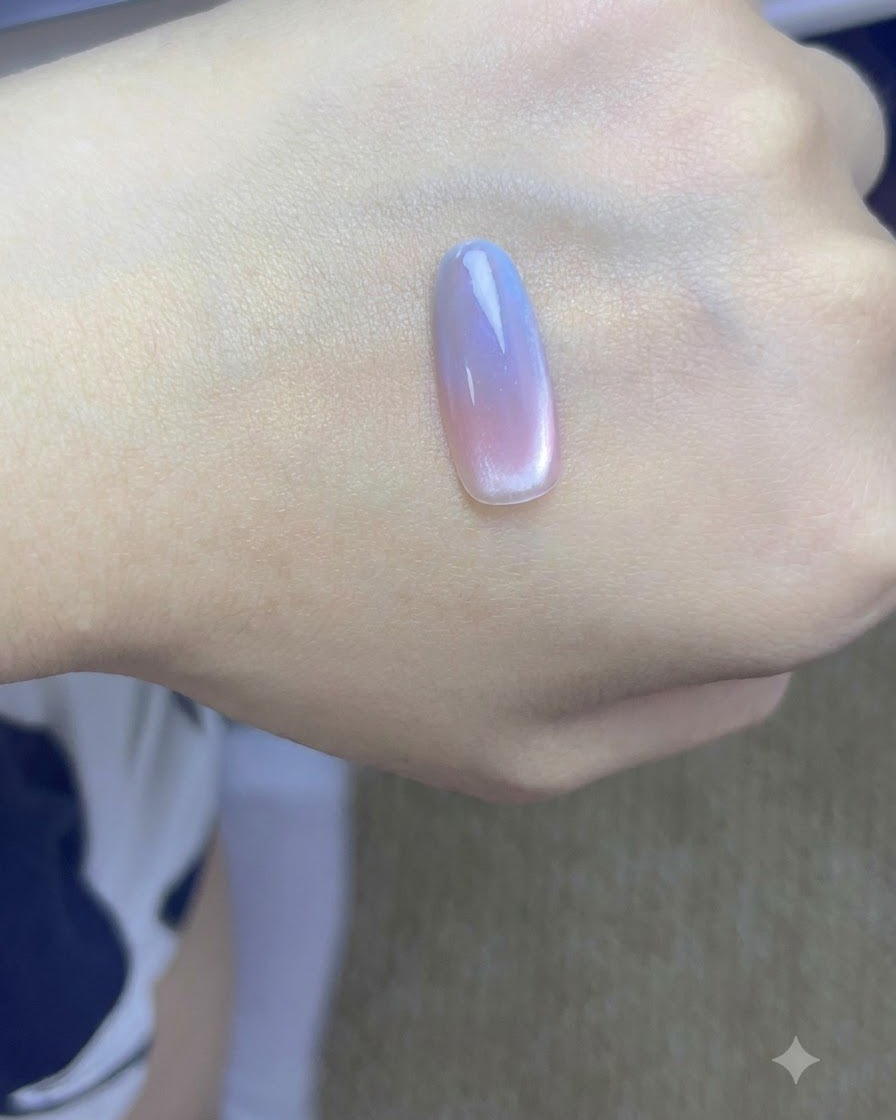 Una mano con uñas cat-eye degradadas terminadas curándose bajo una lámpara UV profesional para uñas.