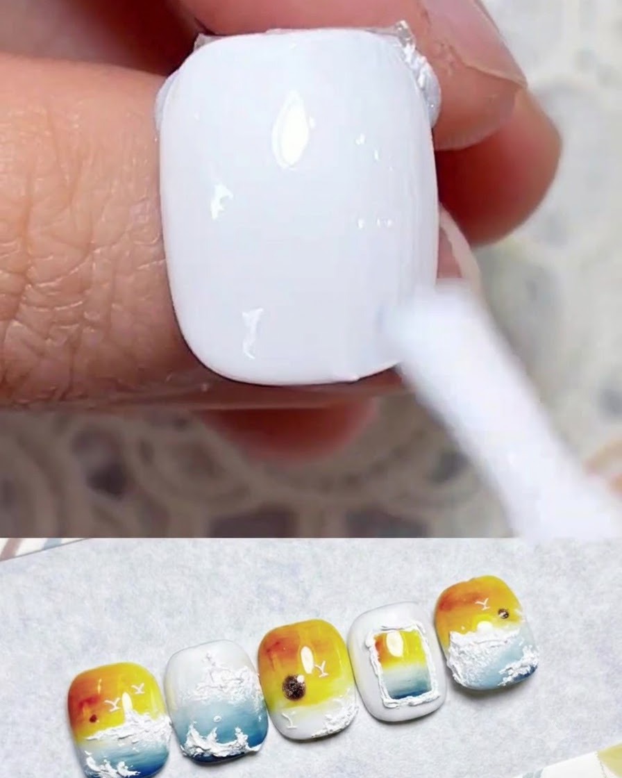 Un pincel de uñas aplicando una capa suave de esmalte en gel blanco lechoso sobre una uña natural.