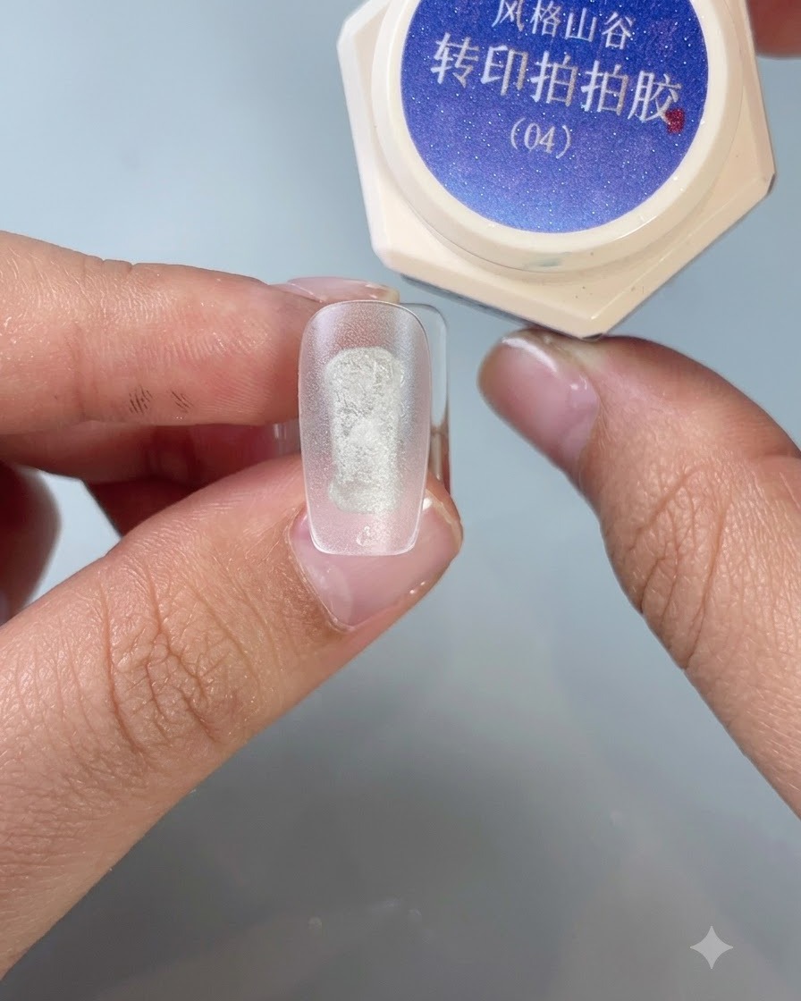Un pincel aplicando gel de transferencia para estampado número 4 en el centro de una punta de uña de práctica esmerilada.