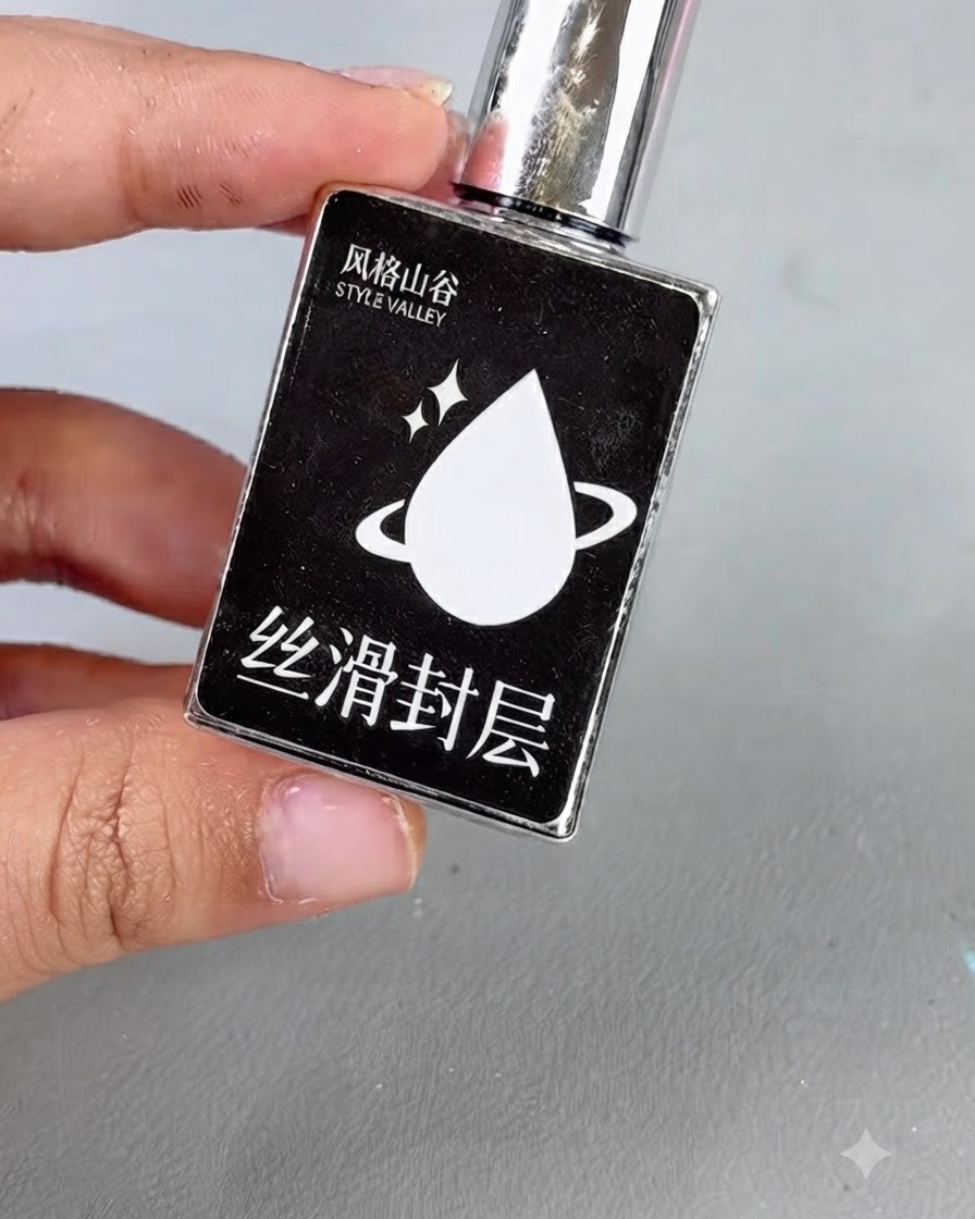 Una botella negra con tapa plateada y un icono de gota blanca etiquetado con texto, que representa gel de capa superior lisa.