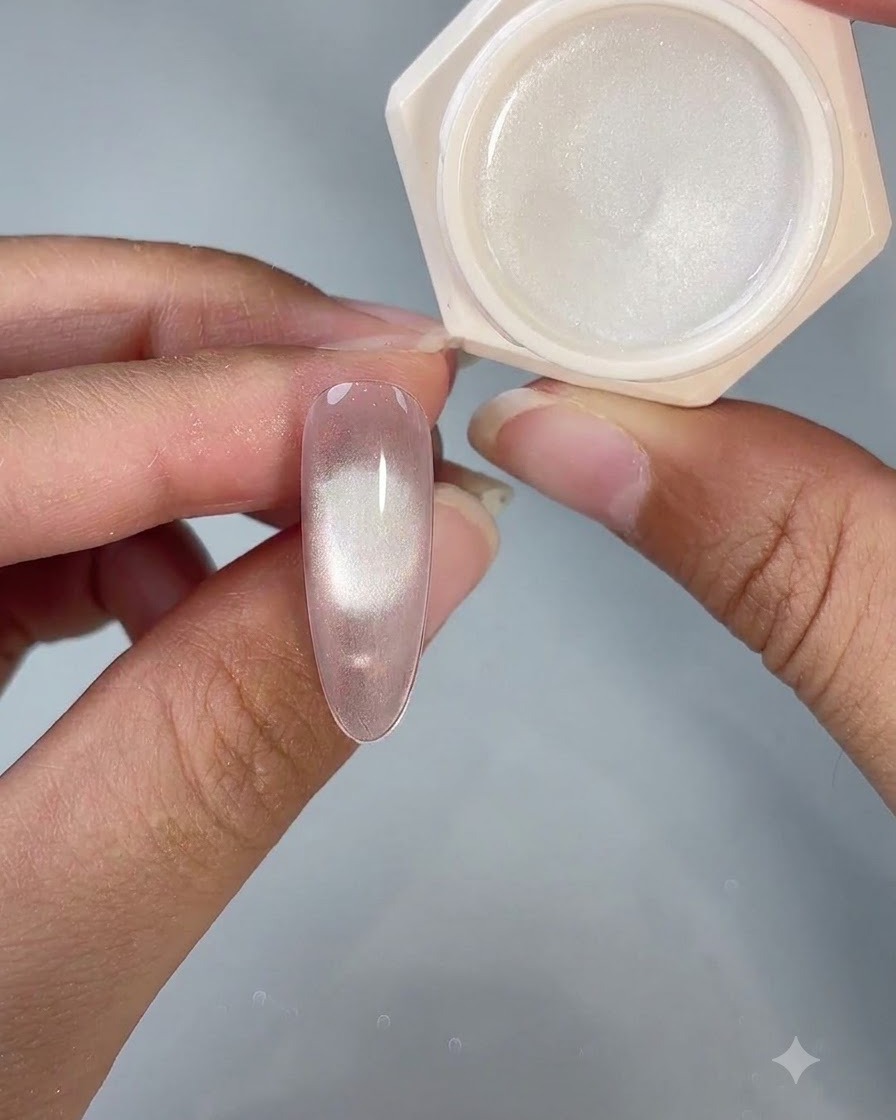 Una uña de gel ojo de gato terminada que se muestra junto a su frasco de producto abierto bajo iluminación de estudio.