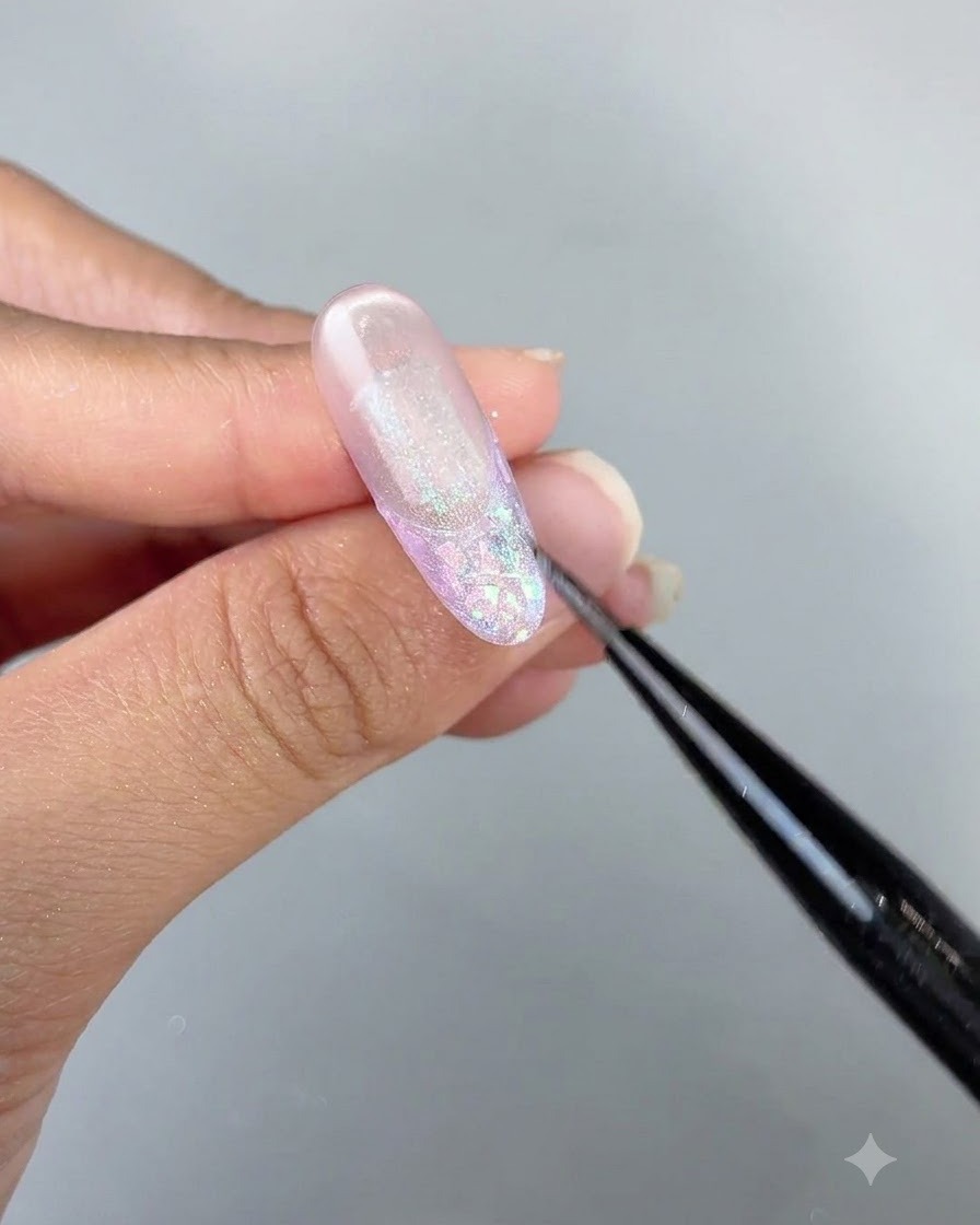 Un primer plano detallado de un pincel perfeccionando los detalles de gel ojo de gato en un diseño de uña largo y brillante.