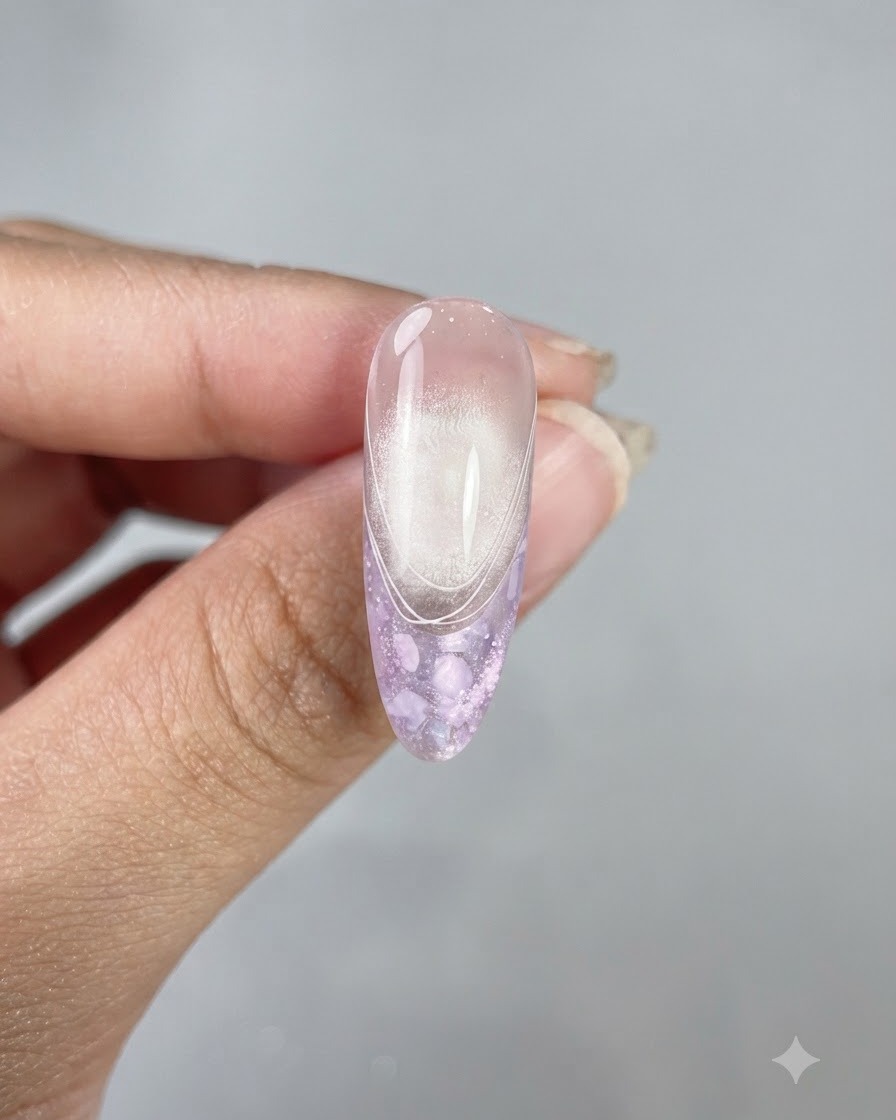 Una uña larga y almendrada terminada que muestra un top coat brillante, un acabado de ojo de gato y delicadas líneas francesas blancas.