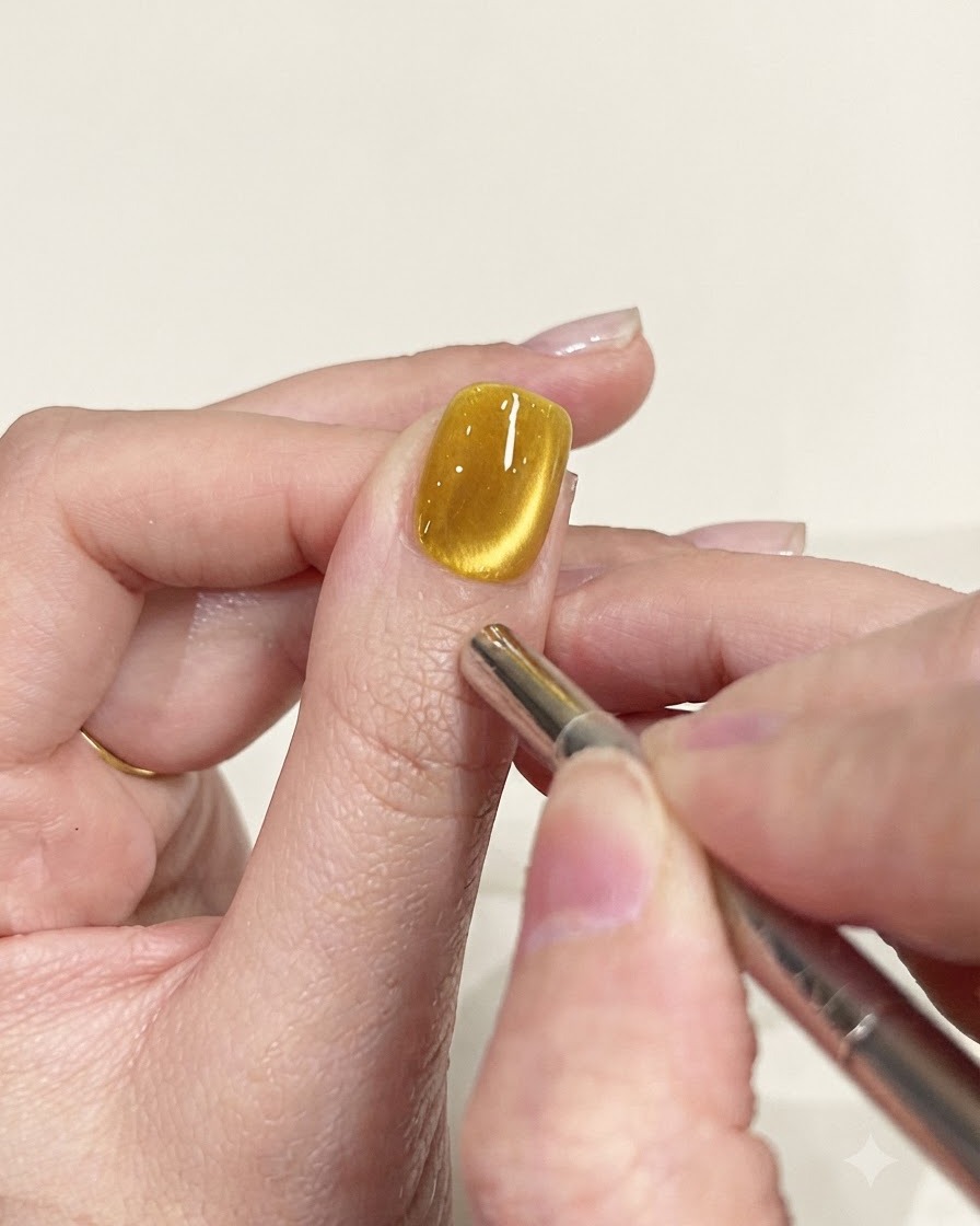 Un lápiz magnético de precisión que se utiliza para refinar la trayectoria del brillo en una uña de ojo de gato amarillo.
