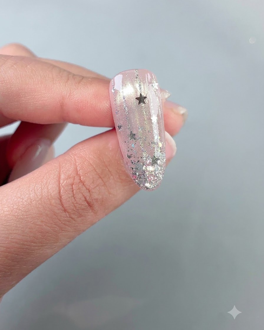 Un diseño de uñas brillante con estrellas terminado y sostenido contra un fondo neutral.