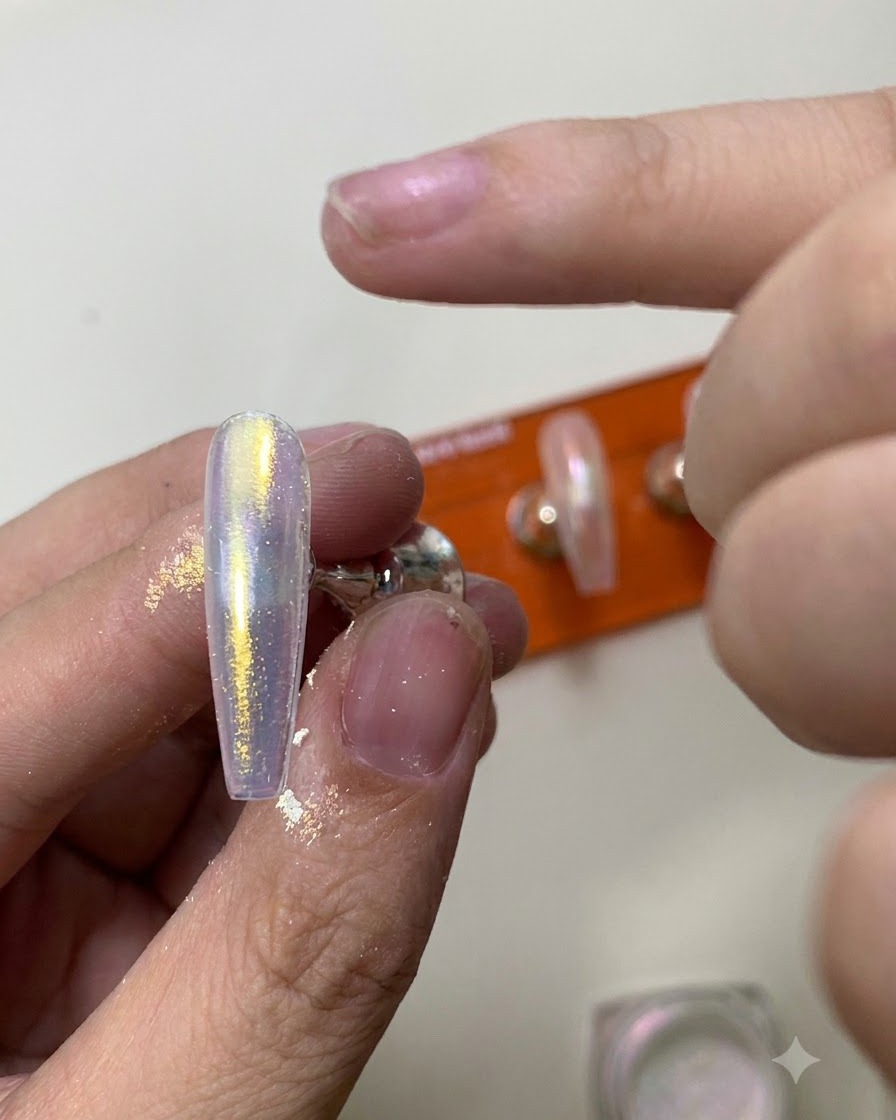 Una herramienta de silicona frotando polvo cromo aurora brillante sobre la superficie de una uña brillante.