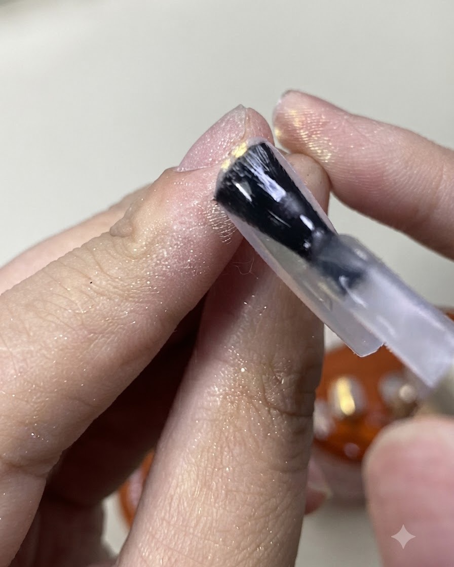 Un pincel pintando un top coat mate sobre el acabado de uñas con polvo aurora brillante.