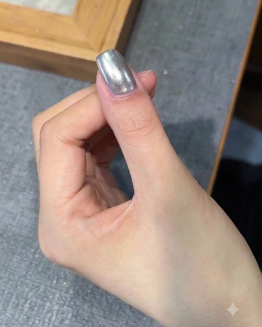 Un pincel aplicando una capa de gel base sobre la uña con acabado cromo.
