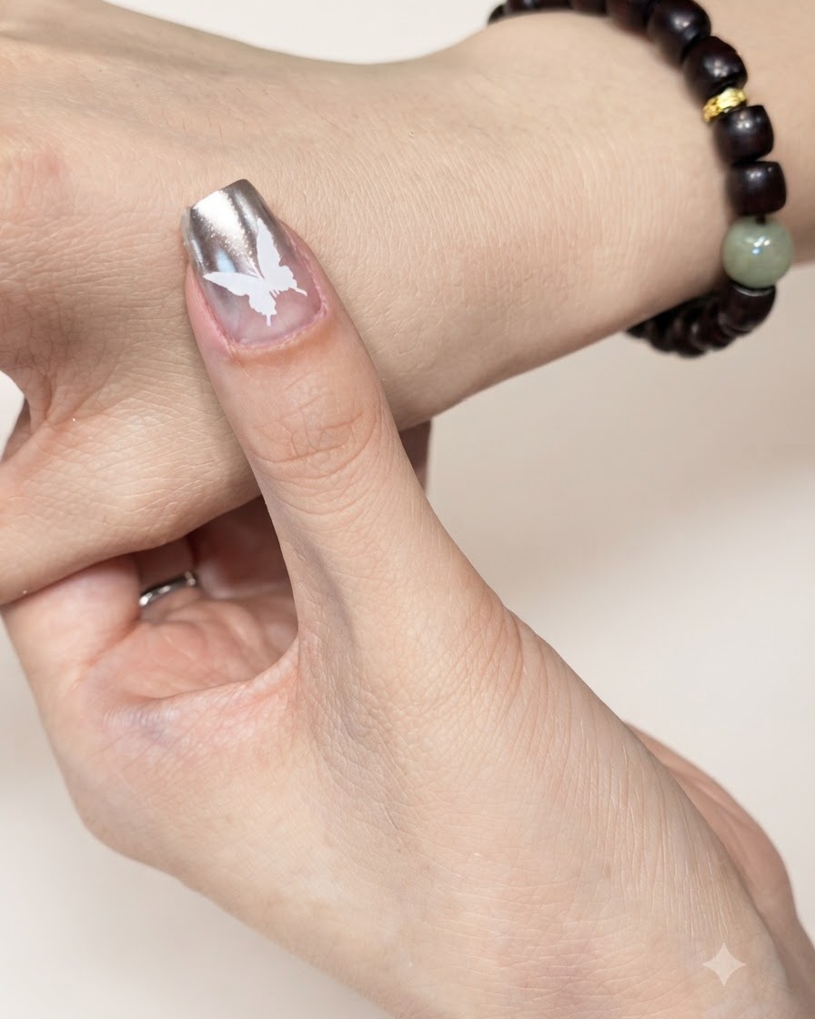 Una uña manicurada con un diseño de mariposa blanca posicionada bajo una lámpara de curado UV o LED.