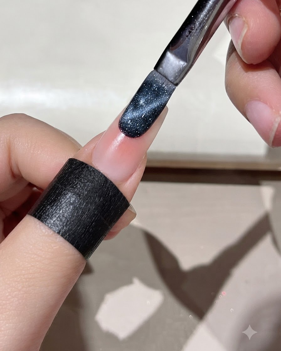 Un pincel aplicando gel de ojo de gato azul oscuro en el borde de una uña preparada.