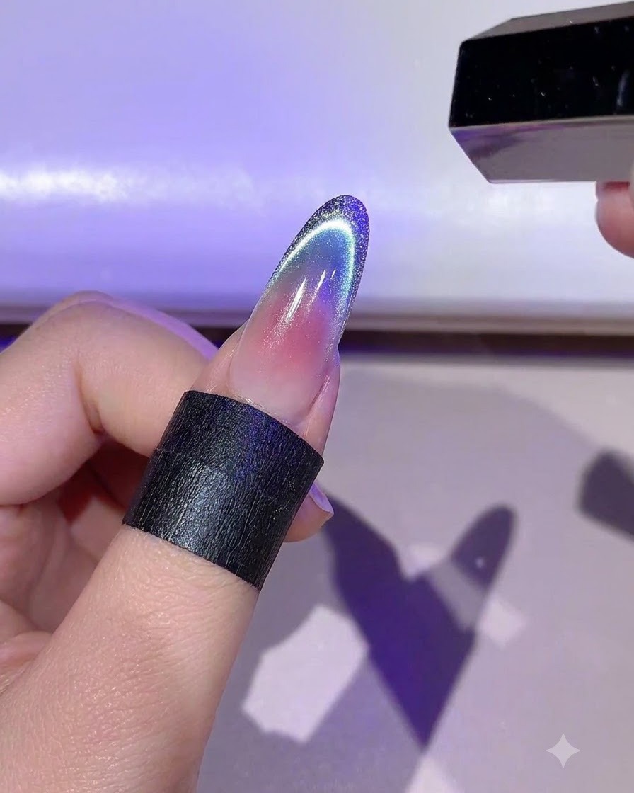 Una mano sosteniendo una mini lámpara LED curando el detallado delineado de gel dorado en una uña.