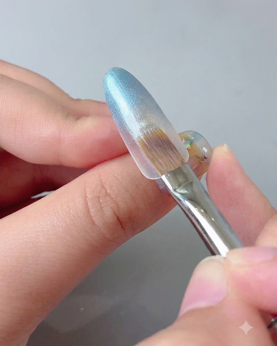 Una herramienta magnética sostenida cerca de la punta de una uña con gel azul para concentrar el brillo de ojo de gato.