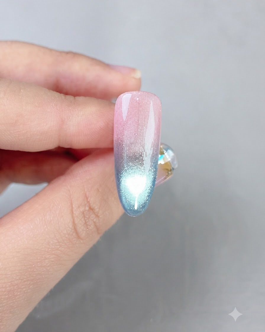 Una uña con degradado rosa y azul terminada que muestra una línea de reflexión de ojo de gato brillante en el centro.