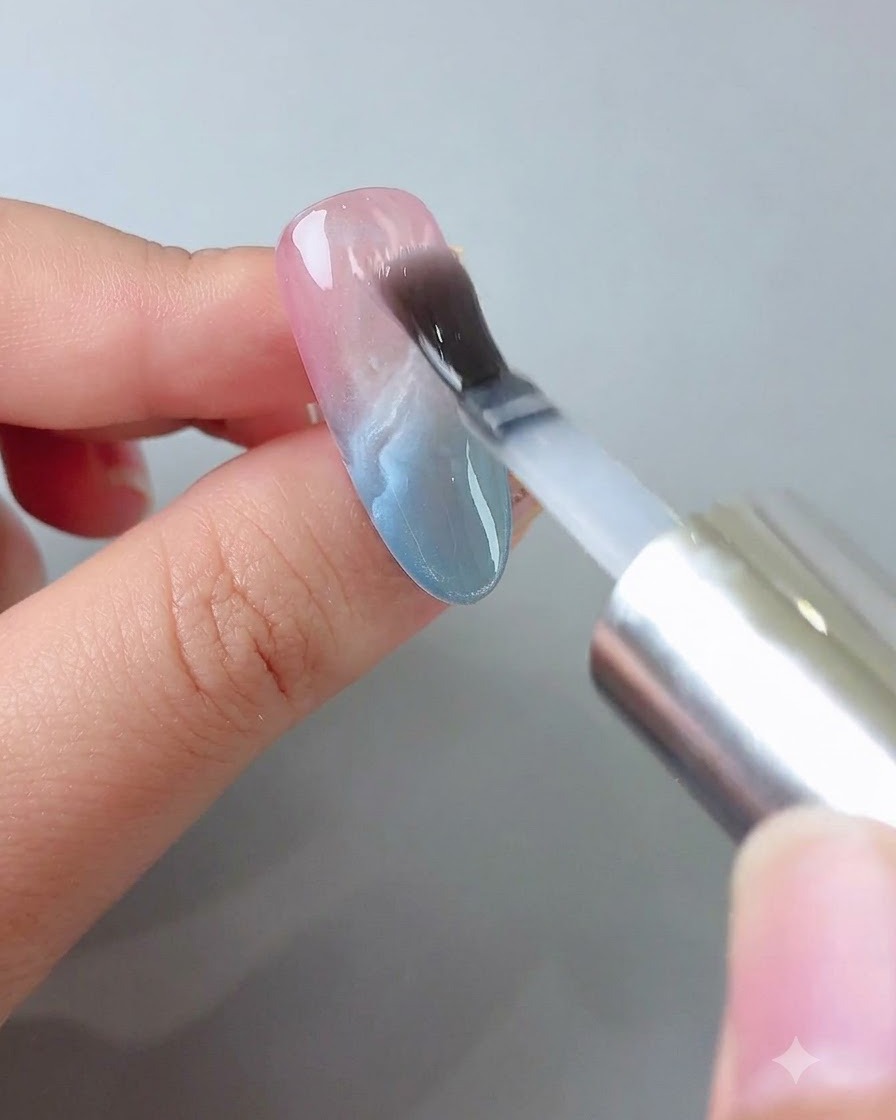 Un pincel aplicando una capa transparente de gel de construcción suavemente sobre la uña decorada.