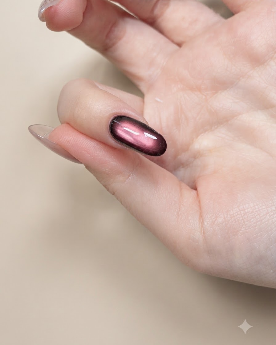 Un pincel fino para nail art pintando contornos negros de alas de mariposa en una uña nude.