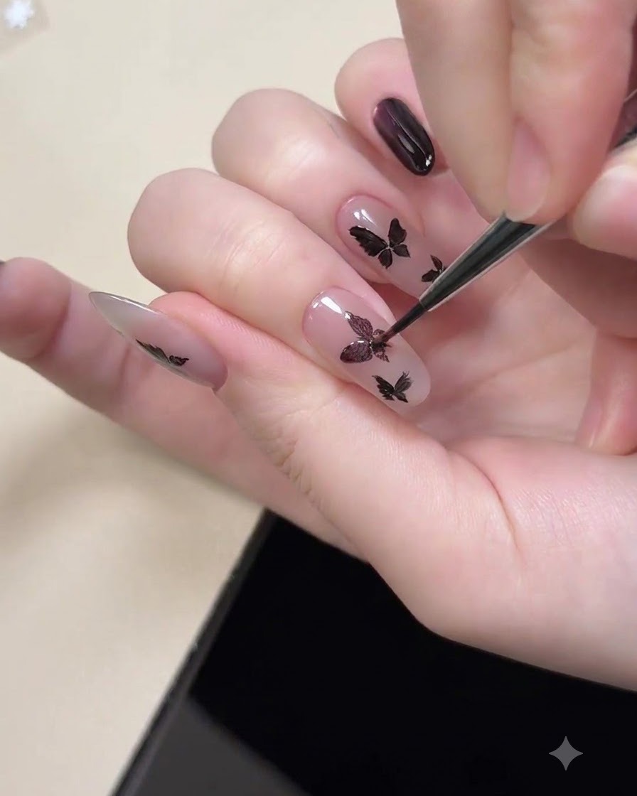 Una herramienta magnética sostenida cerca de una uña para magnetizar el brillo de ojo de gato morado dentro de las formas de mariposa negras pintadas.
