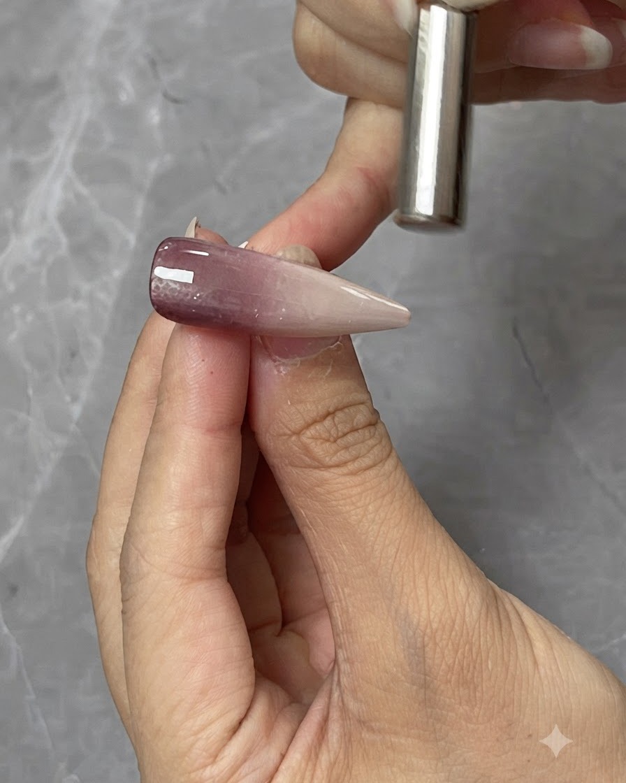 Ein zylindrischer Magnet wird dicht über eine Cat-Eye-Gel-Nagelspitze gehalten, um die magnetische Lichtreflexion zu formen.